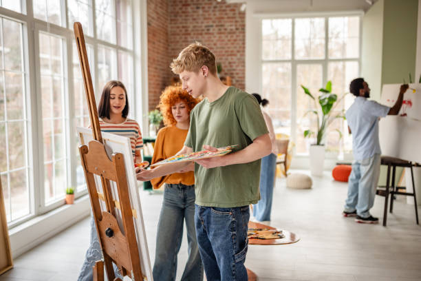 istock Young artists enjoy a collaborative painting session in a vibrant art studio with natural light 2206071021