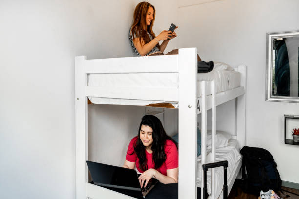 Roommates using laptop and mobile phone in a hotel room