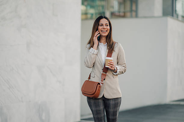 istock Businesswoman walking and talking on phone while holding coffee 2206073122
