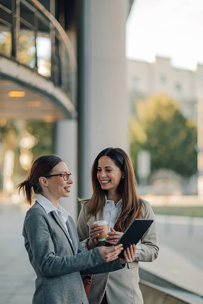 istock Two businesswomen having a conversation and using a digital tablet outside office building 2206073668