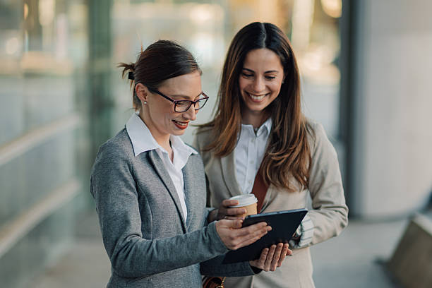 istock Businesswomen using digital tablet and drinking coffee outdoors 2206073672