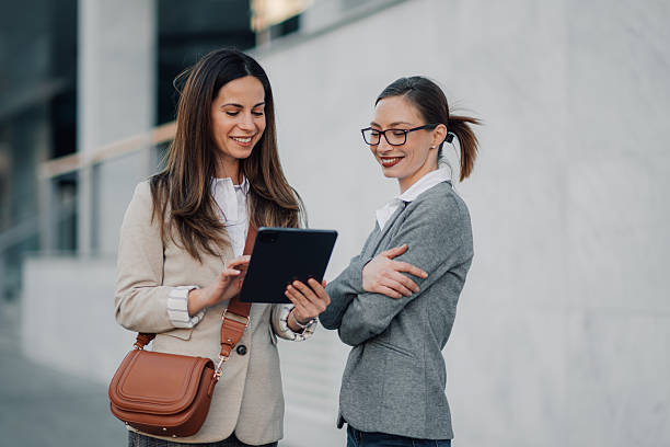 istock Two businesswomen using digital tablet outside office building 2206073673