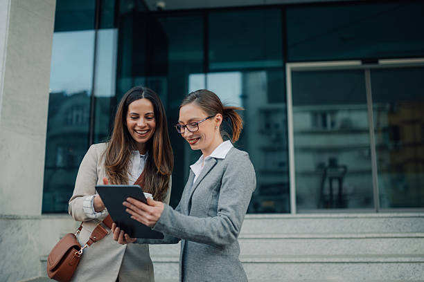 istock Businesswomen using digital tablet outside office building 2206073693