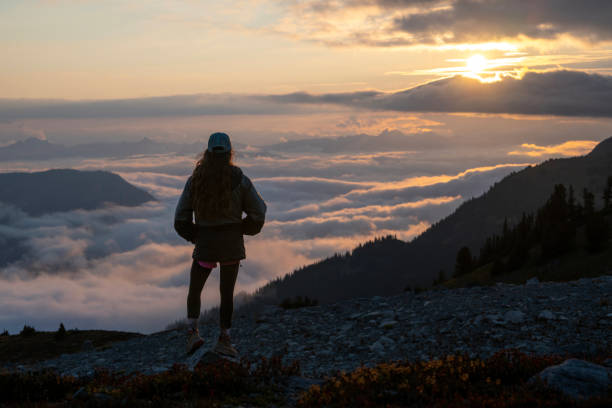 istock Young woman looks over cloudscape from mountain top 2206075840