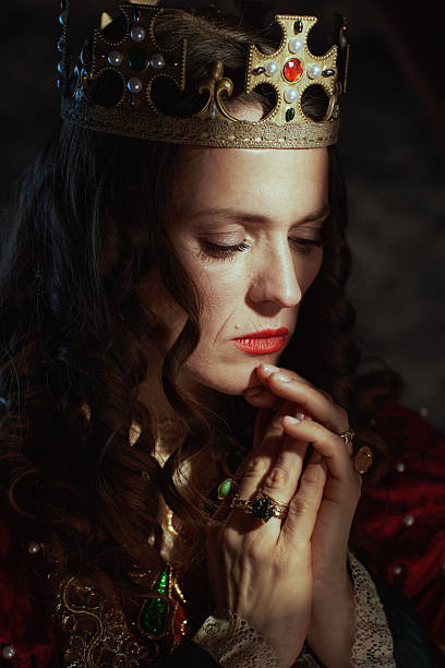 istock medieval queen in red dress with crown praying 2206076306