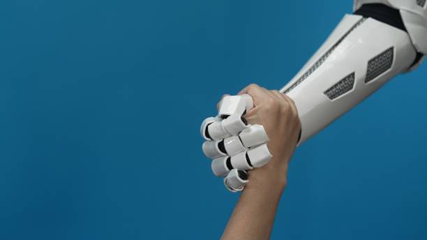 istock Human and Robotic Hands Shaking Against a Blue Background 2206078039