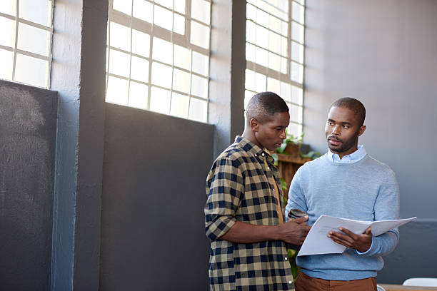 istock Focused African businessmen discussing paperwork together in an office 2206083074