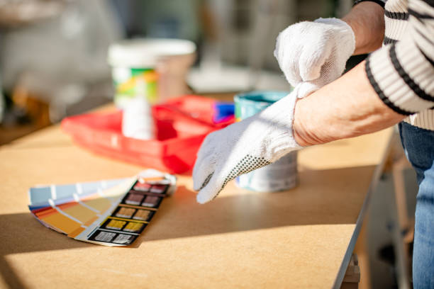 Close-up view of a senior woman putting on gloves before starting a wall painting project.