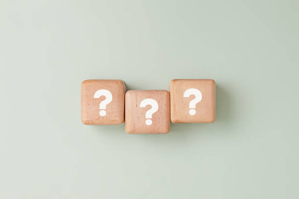istock Three wooden blocks with white question marks in straight line against light pale green background. Symbolizing for concepts like problem-solving, brainstorming, or business strategy presentations. 2206091413