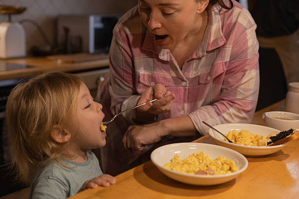 istock mother feeds her son scrambled eggs with a fork in the kitchen 2206091883