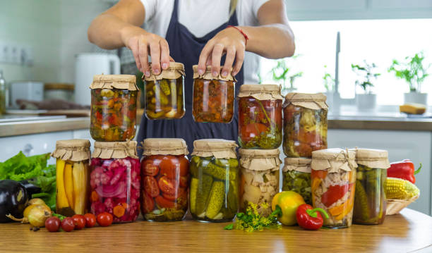 istock Woman canning vegetables in jars in the kitchen. Selective focus. 2206092394