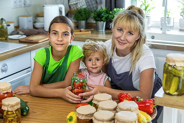 Healthy homemade eco-friendly food. Mother teaches little daughter how to make homemade dill cucumber pickles in summer with homegrown cucumbers.