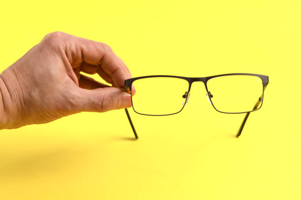 istock Hand holding plastic black glasses, isolated on yellow background. 2206093486