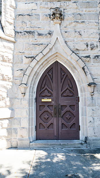 Brown wooden double gate with arch in stone wall