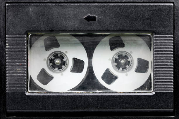 A high-key, clean studio shot of a transparent audio cassette tape laying flat on a pure white surface. The clear plastic casing reveals the intricate internal mechanisms, including the brown magnetic tape, white reels, and copper-colored pressure pad. This isolated object is perfect for graphic designers looking for nostalgic music icons, retro-themed layouts, or concepts related to recording and history.