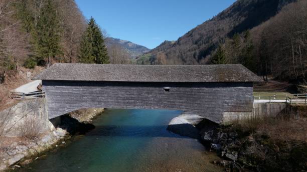istock A covered wooden bridge spans a clear river in a scenic valley 2206098064