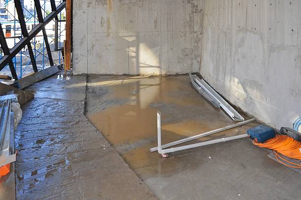 istock Water reflects daylight on the concrete floor of an active construction site in the interior. 2206099699