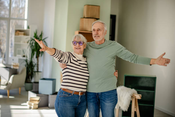 istock Senior couple enjoys their new home together while decorating and unpacking boxes in a bright, cheerful living room 2206101426