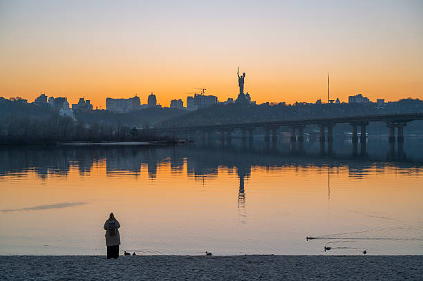 Daily life in Ukraine. Kyiv city in 2025 Kyiv, Ukraine - 20th March, 2025: People resting at beach, of Dnipro river , against scenic view of famous Mother Ukraine monument - symbol of Ukrainain struggle agaisnt full scale russian invasion in Ukraine ( 24th Feb.2022) and part of the National Museum of the History of Ukraine in the Second World War russian invasion of ukraine 2022 2025 stock pictures, royalty-free photos & images