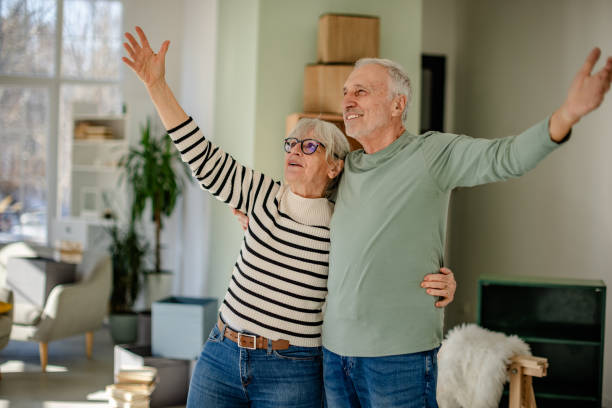 istock Senior couple joyfully celebrates moving into their new home while unpacking boxes and decorating their living space 2206106534