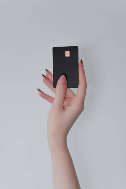 istock A hand with a minimalist manicure holds a sleek black card against a plain background. The card features a gold chip, suggesting premium quality and exclusivity. 2206109263