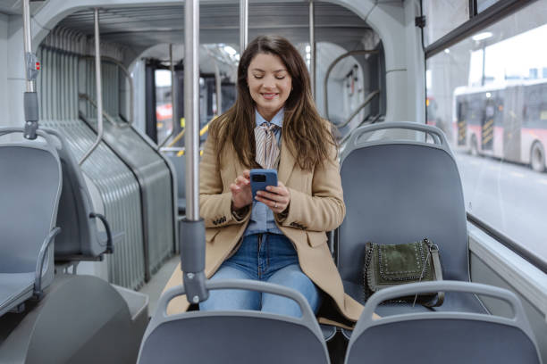 istock Smiling woman using smartphone while riding on a modern city bus 2206112691