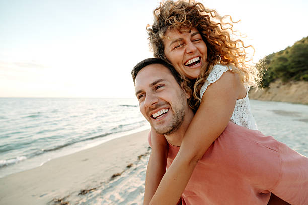 istock Man carrying his wife on back while enjoying day on a beach 2206113899