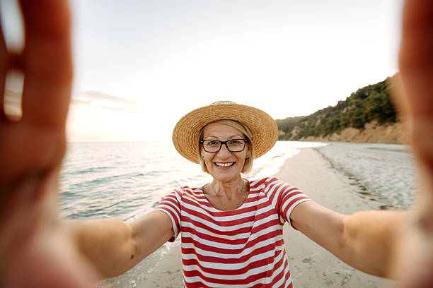 istock Mature smiling woman taking selfie while enjoying sunset on a beach 2206113975