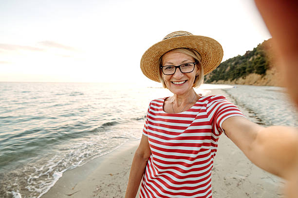 istock Mature smiling woman taking selfie while enjoying sunset on a beach 2206113976
