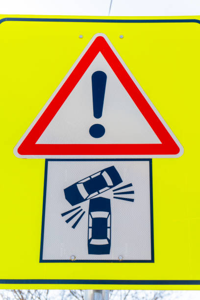 Bright yellow warning sign alerts drivers of possible vehicle skidding risks on icy roads. The sign features an image of cars losing traction, emphasizing safety awareness.