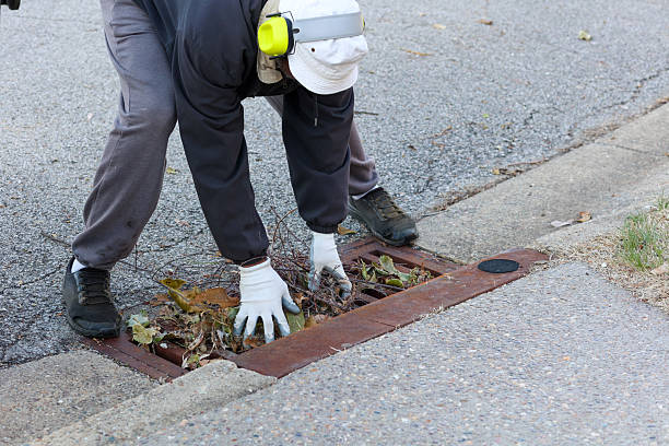 a-portrait-of-a-black-man-picking-up-leaves-on-a-sewer-drain.jpg