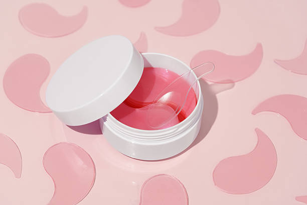 istock Pink hydrogel patches in a white jar with a transparent spatula on a pink background, surrounded by a pattern of patches. Concept of moisturizing, nourishing, and treating under-eye skin. 2206118538