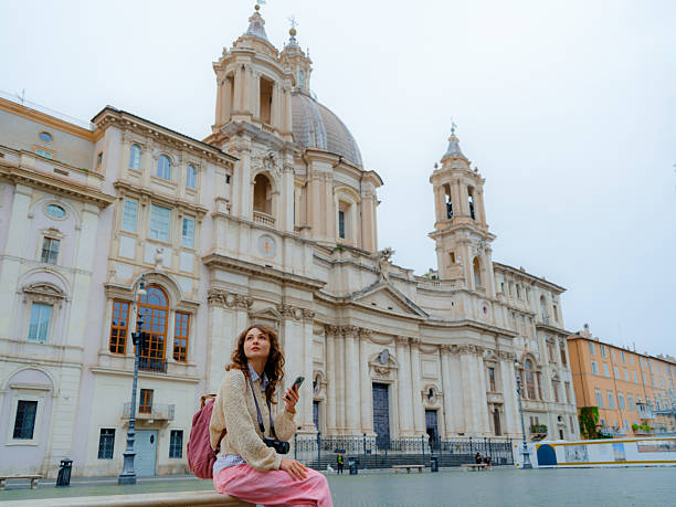 istock Woman using smartphone sitting on a bench on Plaza Navona during her visit in Rome 2206120017