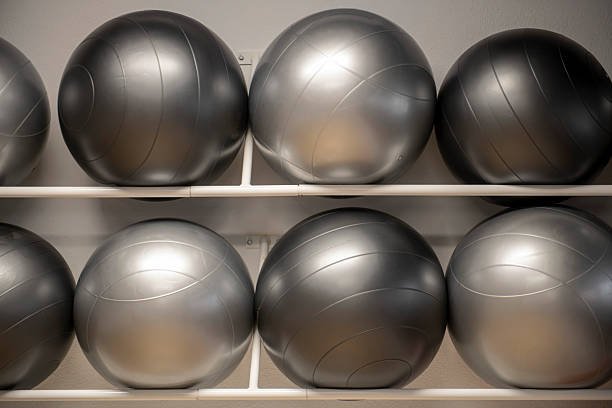 Silver exercise balls are neatly arranged on a rack, ready for use in a gym or fitness studio, promoting health and wellness