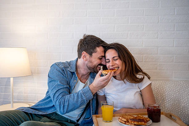 istock Happy couple sharing breakfast and showing love on sofa 2206120534