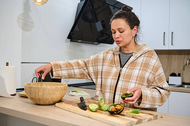 istock Woman Preparing Avocado Salad in a Modern Home Kitchen Setting 2206120740