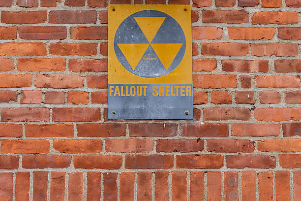 A historic yellow silver fallout shelter sign on an exterior red brick wall