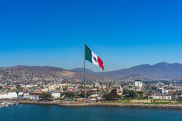 Ensenada, BC, Mexico – February 24, 2025: View of the waterfront area of Ensenada, Mexico, with the large landmark Mexican flag flying over the city and mountains.