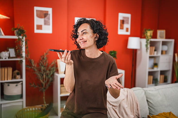 istock mature woman record voice message while sit on sofa and pack suitcase 2206123286