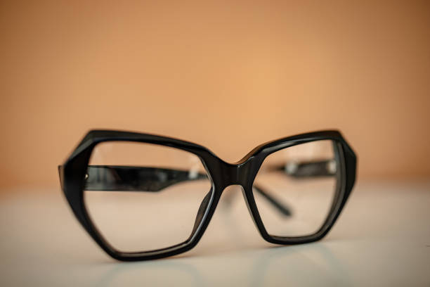 istock Unique black eyeglasses resting on a surface with a warm background that highlights modern design aesthetics 2206123375