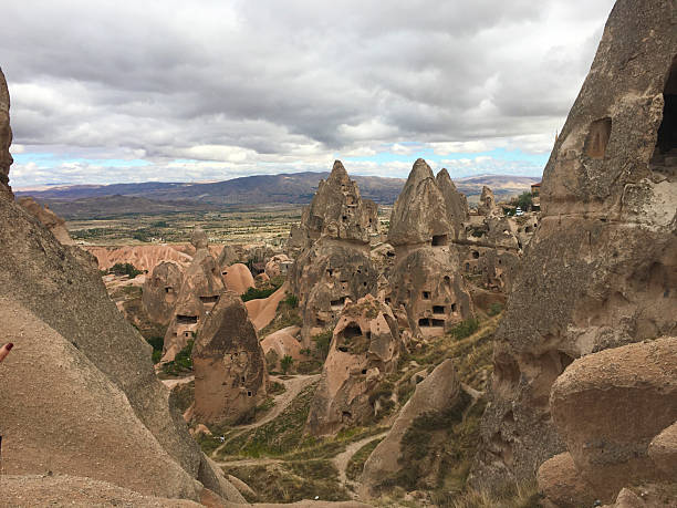 istock Red-hued rock formations featuring small caves in rugged terrain 2206123429