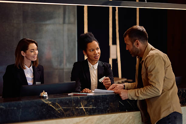 istock Black female hotel manager assisting a guest with paperwork at reception desk 2206124092