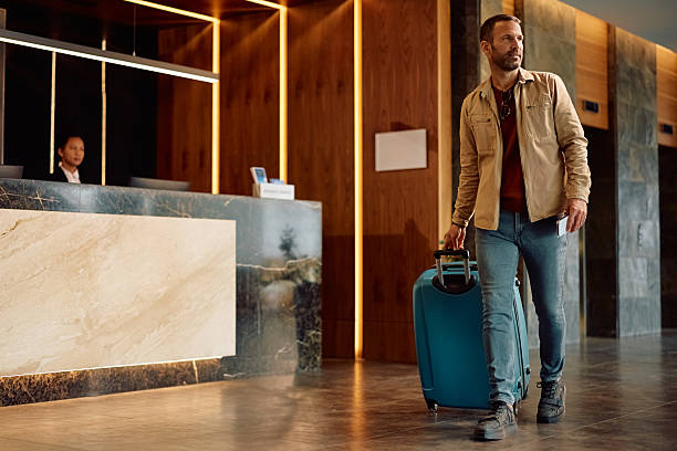 istock Male traveler with a suitcase walking through hotel hallway. 2206124154