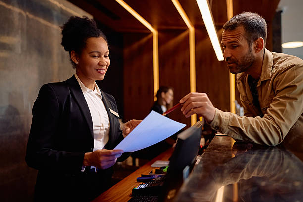 istock Happy black hotel manager assisting a guest with paperwork at reception desk. 2206124269