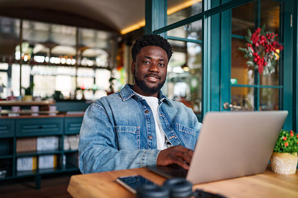 istock Young Black Man Cheerfully Looking at Camera While Sitting with Laptop 2206125126