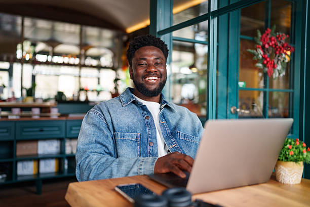 istock Young Black Man Cheerfully Looking at Camera While Sitting with Laptop 2206125130