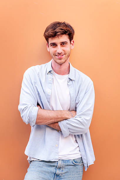 istock smiling young man standing with arms crossed 2206127417