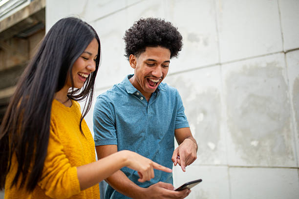 istock cheerful young couple pointing to mobile phone 2206127473