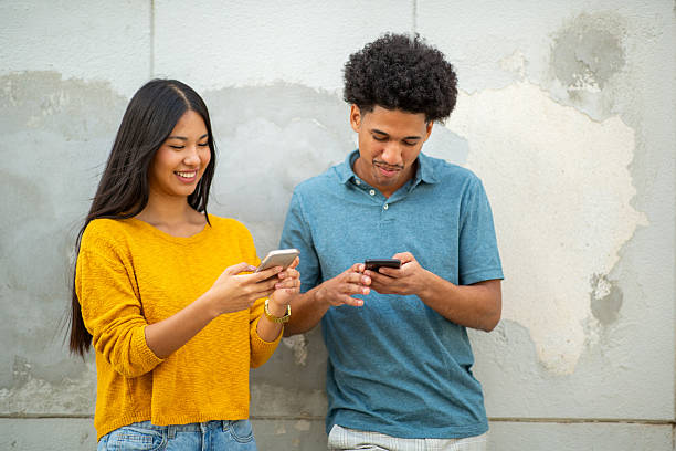 istock smiling young couple using mobile phones 2206127483
