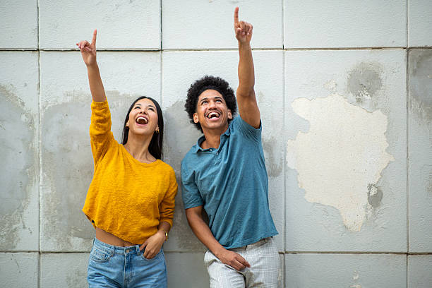 istock cheerful young couple pointing fingers 2206127485